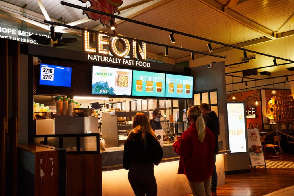 Customers waiting to order at a leon fast food restaurant counter.
