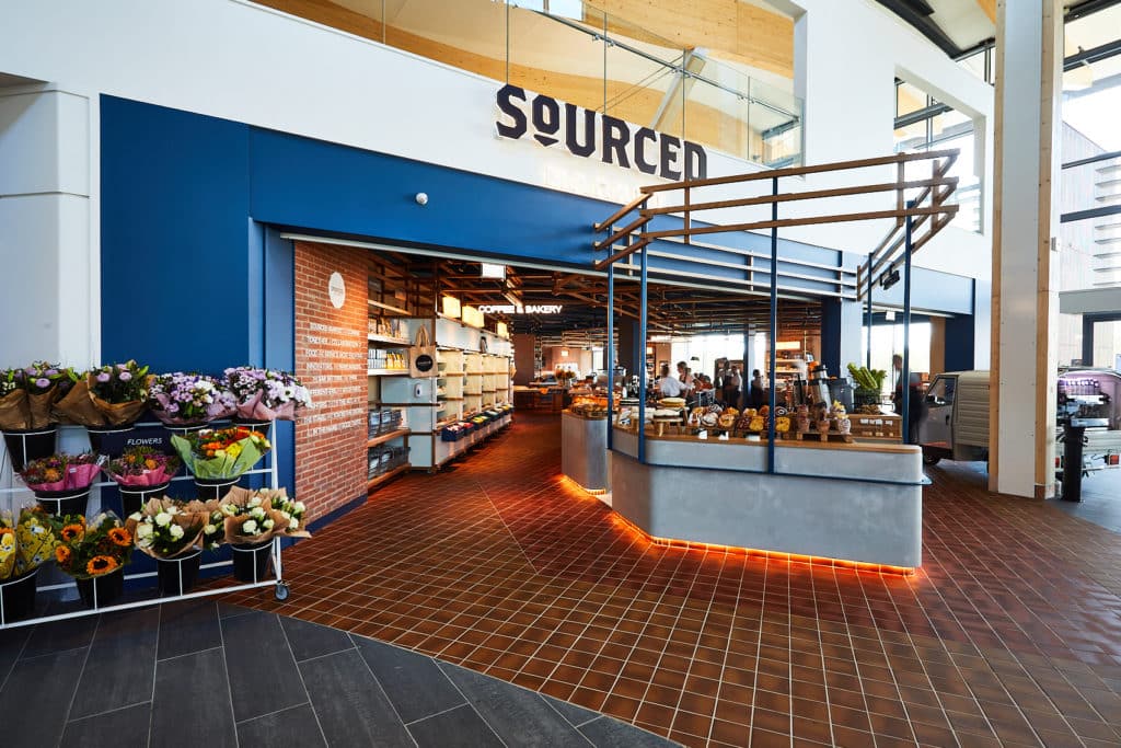 Modern market interior with fresh produce, a bakery section, and EV Chargers.
