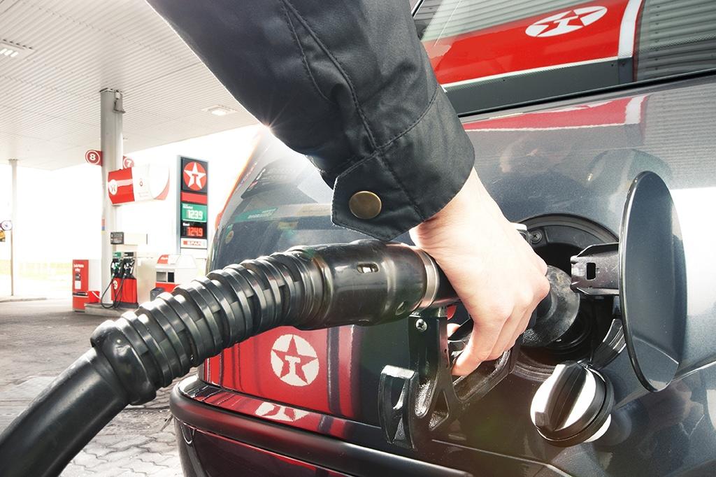 Person refueling a car at a gas station.