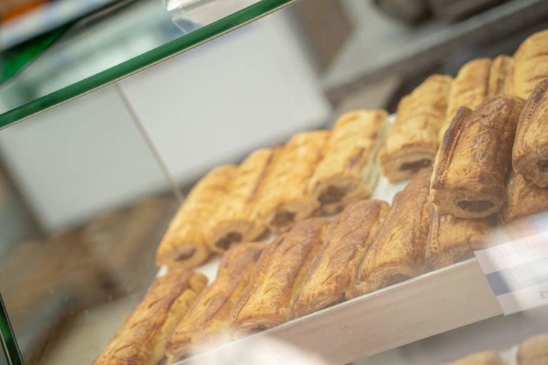 Freshly baked pastries displayed in a glass case at a motorway service area bakery.