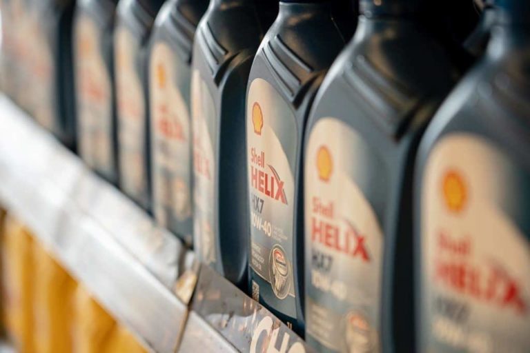 Row of shell helix motor oil bottles on a shelf at a motorway service area, with focus on the label of one bottle, in a blurred store setting.